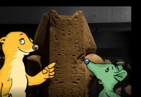 Die Museumsmaskottchen Isi und Usi stehen vor eine Statue