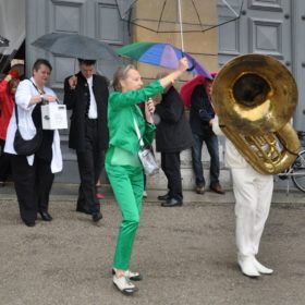 Ruth Geiersberger in grünem Anzug neben einem Tuba-Spieler