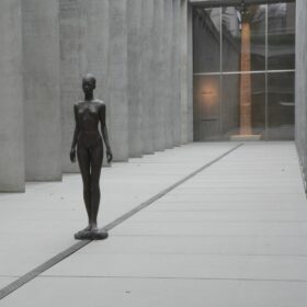 Blick in das Atrium des Museums. Darin steht die schwarze Bronzestatue einer nackten Frau.