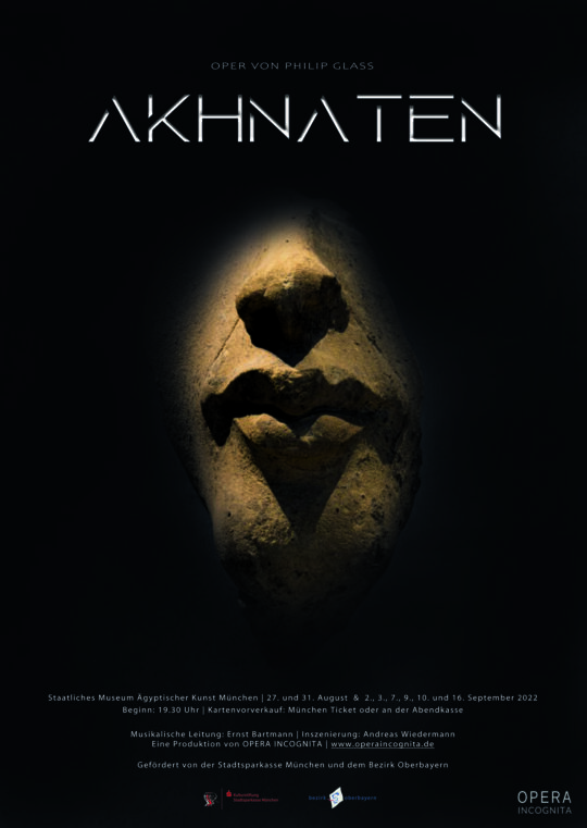 Plakat der Akhnaten-Aufführung der Opera Incognita. Aus der Schwärze tritt wie in einem Lichtkegel das Gesichts des Statuenfragments des Echnaton hervor, nur Mund und Nase sind zu erkennen.