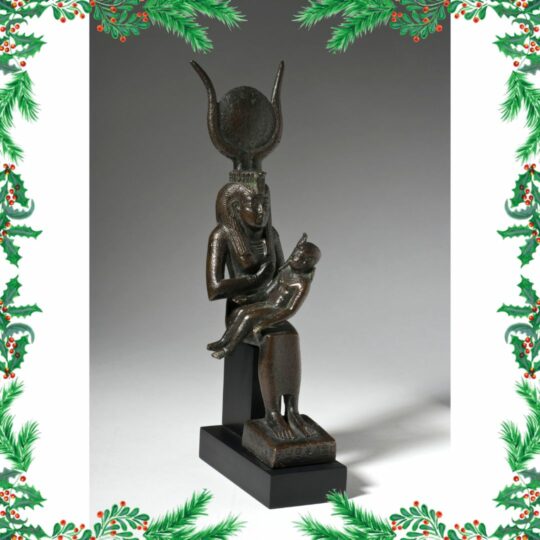 Eine bronzene Isisstatue mit Horuskind auf dem Schoß, rundherum um das Bild eine Weihnachts-Tannengirlande