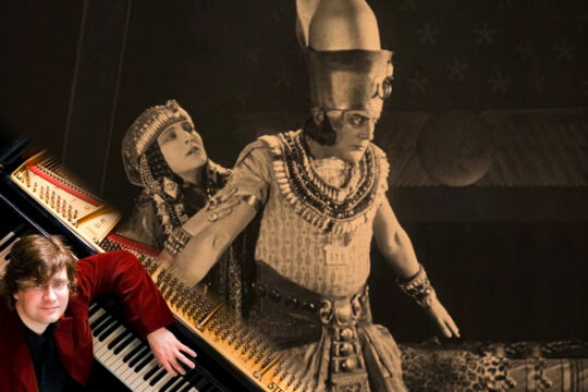 Ein Ausschnitt aus dem Stummfilm "Das Weib des Pharao" - ein altägyptischer Pharao, nach rechts blickend, hinter ihm eine ägyptische Frau. Unten links in der Bildecke der Pianist Stephan Bothmer vor seinem Flügel