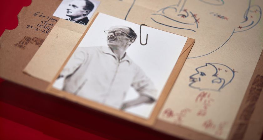 Auf einem mit Kuli vollgekritzelten Papier ist mit einer Büroklammer ein Foto von Adolf Eichmann angeheftet.