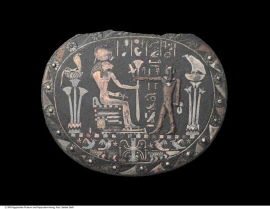 Menit des Harsiese, Relief auf einer ovalen Kupferscheibe, eine löwenköpfige Göttin sitzt vor einem stehenden nackten Jungen