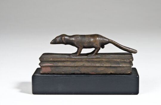 Bronzespitzmaus auf einem kastenförmigen Sarg stehend