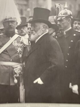 Schwarz-weiß Bild des Bildhauers Adolf von Hildebrand - ein alter Mann mit langem weißen Bart, der einen Zylinder und eine Frack trägt