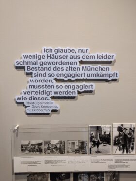 Ein Zitat an einer Wand: "Ich glaube, nur wenige Häuser aus dem schmal gewordenen Bestand des alten München sind so engagiert umkämpft worden, mussten so engagiert verteidigt werden, wie dieses.", Oberbürgermeister Georg Kronawitter, 19. Oktober 1977