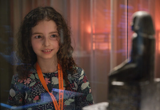 Ein Mädchen schaut eine altägyptische Statue an.