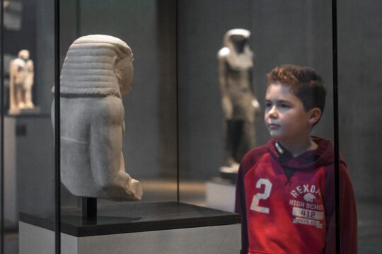 Ein Kind schaut eine ägyptische Statue an