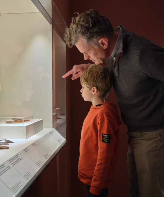 Vater und Sohn vor einer Vitrine mit altägyptischen Originalen