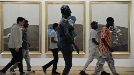 Eine Gruppe Jugendlicher läuft durch ein Kunstmuseum