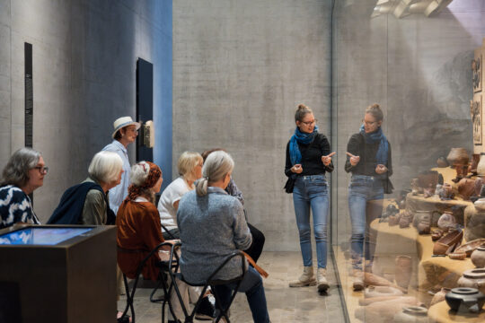 Eine Gruppe älterer menschen lauscht einer Führung im Museum