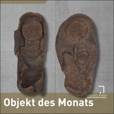 Zwei kleine braune Lederschuhe auf Betongrund, darunter die weiße Schrift: Objekt des Monats