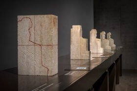 Blick in den Ausstellungsraum Altägypten (er)fassen. Auf den Tischen sind verschiedene Objekte afgestellt, die illustrieren, wie aus einem Steinblock eine Statue wird.